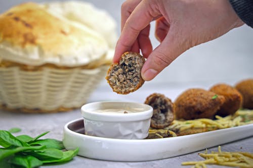 A person dipping a piece of bread into a bowl of food