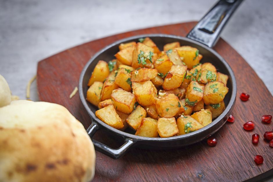 Golden crispy roasted potatoes in a skillet on wooden surface