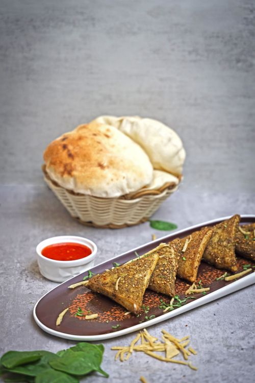 Free A flavorful bread and spiced appetizer dish with dipping sauce on a modern setting. Stock Photo