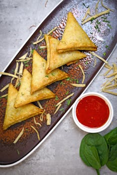 A tempting display of golden samosas with dipping sauce on a stylish plate, perfect for snacks.