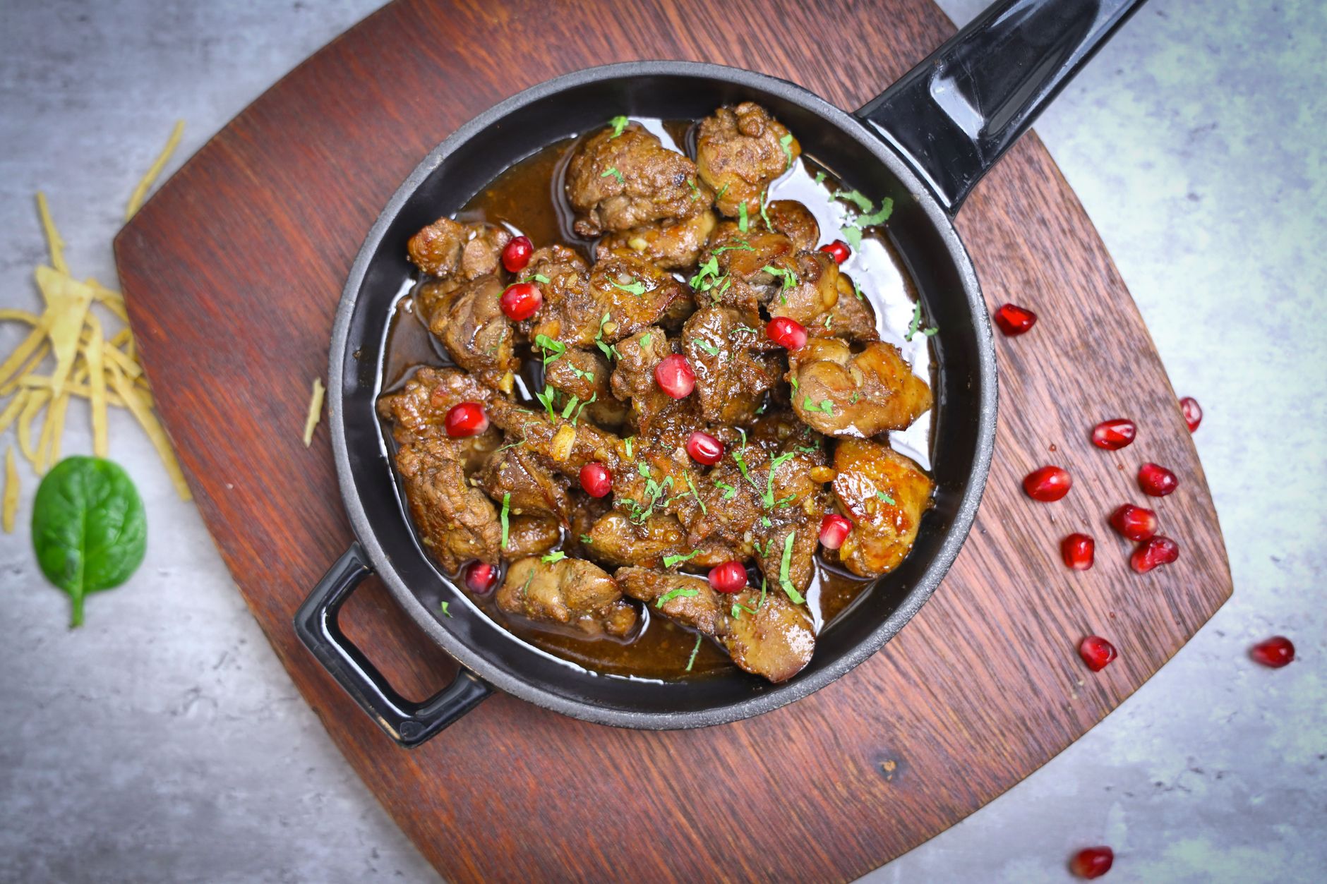 Bowl of dark reddish-brown Persian fesenjan stew with tender chicken pieces in glossy pomegranate walnut sauce, served over rice and garnished with pomegranate seeds