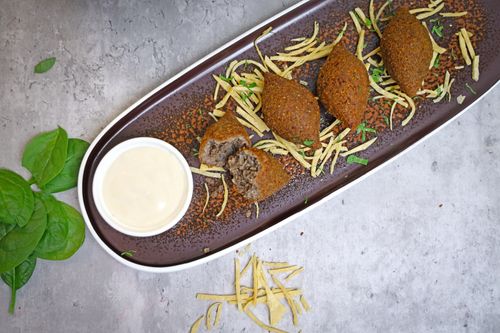 Free A beautifully presented Middle Eastern kibbeh dish with tahini sauce on a rustic plate. Stock Photo