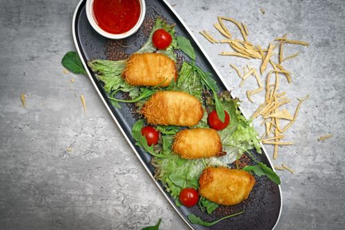 Free Crispy golden appetizers on lettuce with cherry tomatoes and dipping sauce, perfect for a gourmet meal. Stock Photo
