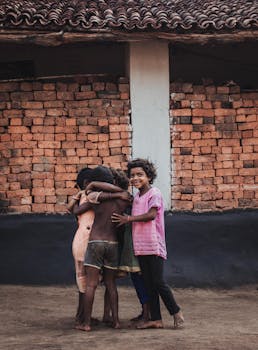 A group of young children joyfully hugging in front of a rustic brick wall, symbolizing friendship and happiness.