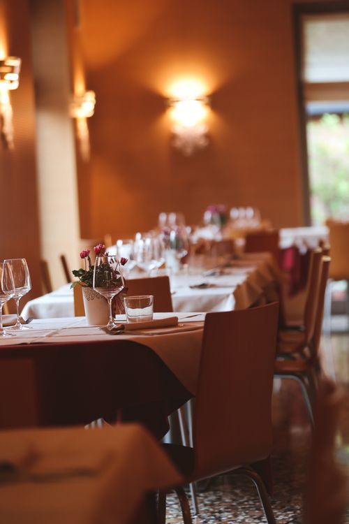Free A warmly lit restaurant interior showcasing elegantly arranged dining tables and chairs. Stock Photo
