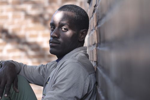 Free Portrait of a thoughtful man sitting by a brick wall, outdoors, in soft light. Stock Photo