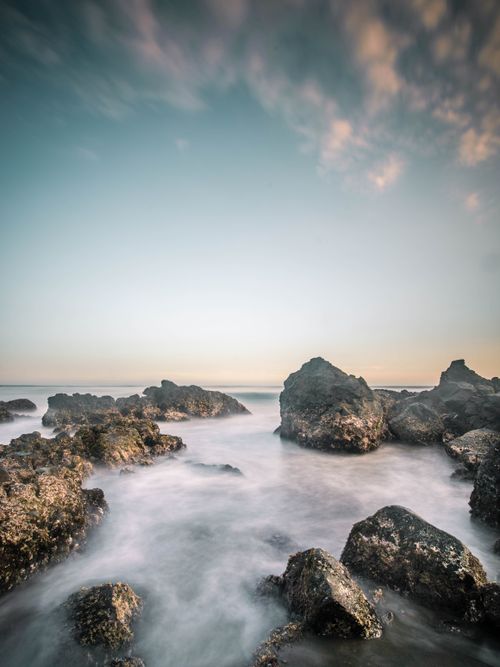 Free Soothing seascape at sunset with ocean waves and rocks in Karanghawu, Indonesia. Stock Photo