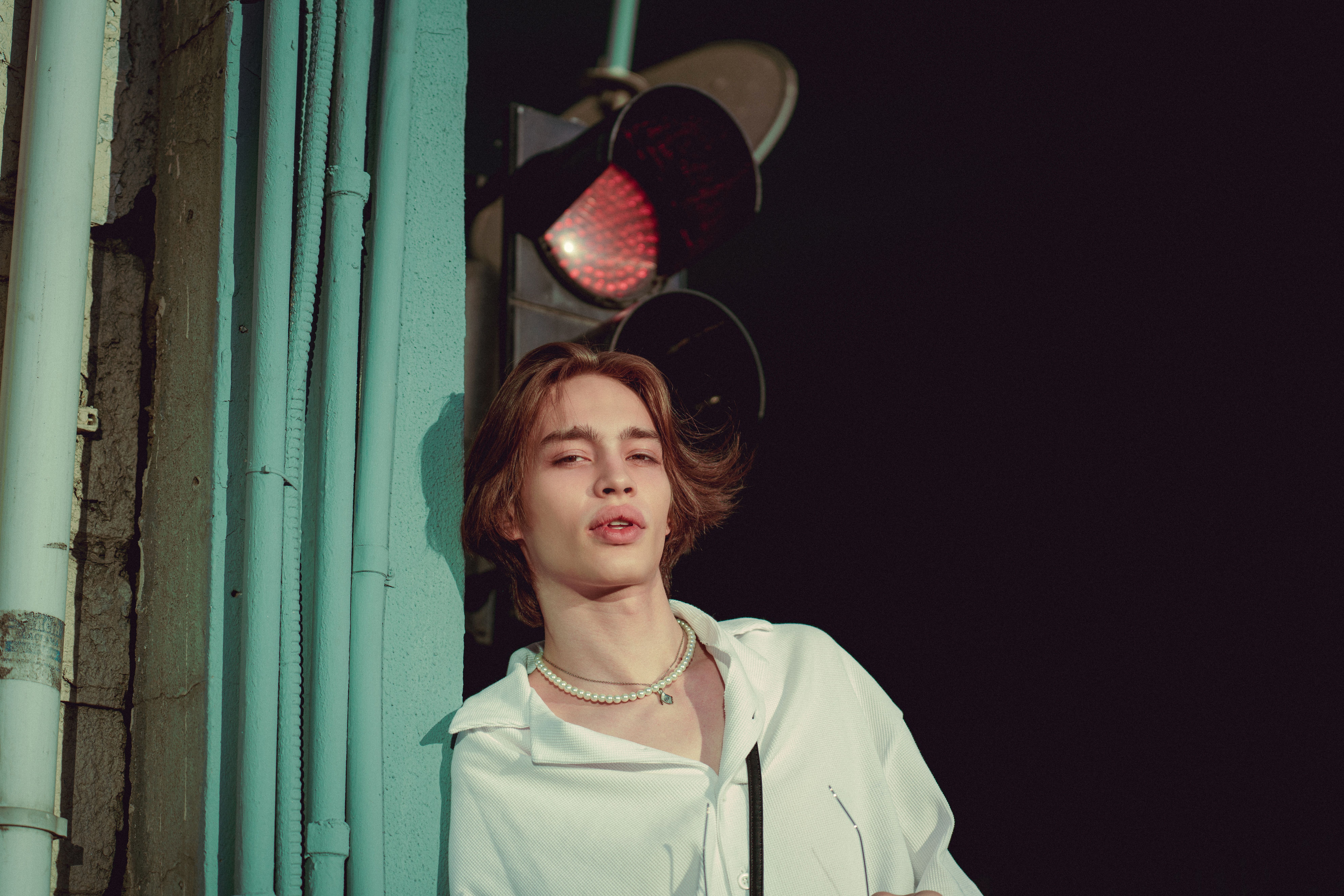 Stylish young adult posing confidently by a traffic light in Istanbul, showing modern fashion sense.