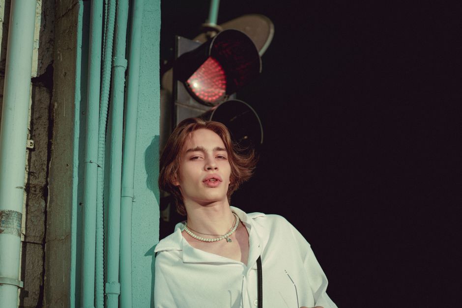 Stylish young adult posing confidently by a traffic light in Istanbul, showing modern fashion sense.