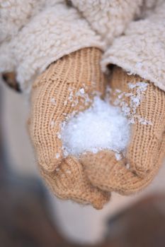 Close-up of gloved hands holding snowflakes, capturing the essence of winter.