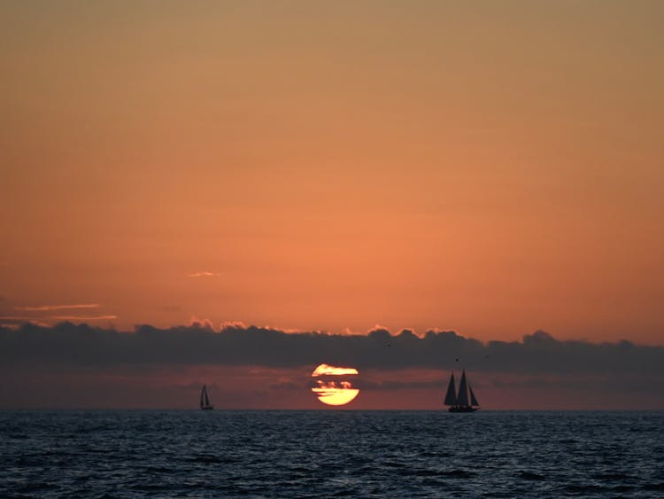 Silhouette Of Sailboats On Water During Sunset