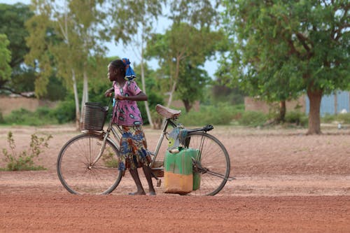 Girl Pushing a Bicycle on a Field 