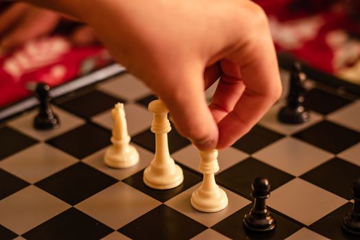 Close-up of a chess game in progress with a hand making a strategic move on the board.