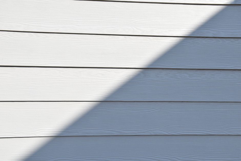 Close-up of a white wooden wall featuring a bold diagonal shadow.