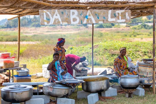 African women cooking in pots at a market stall, showcasing traditional culinary practices.