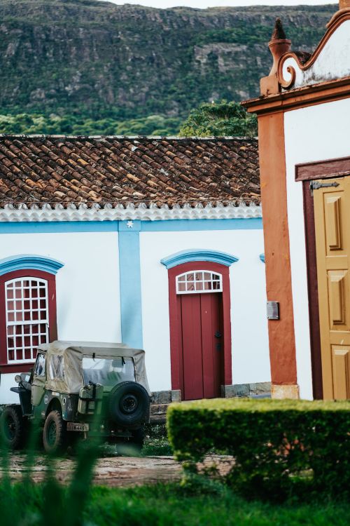 Free Charming colonial architecture in Tiradentes with vintage jeep in the foreground and lush mountains in the background. Stock Photo