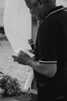 Monochromatic photo of an elderly man giving a speech at a beachside event.