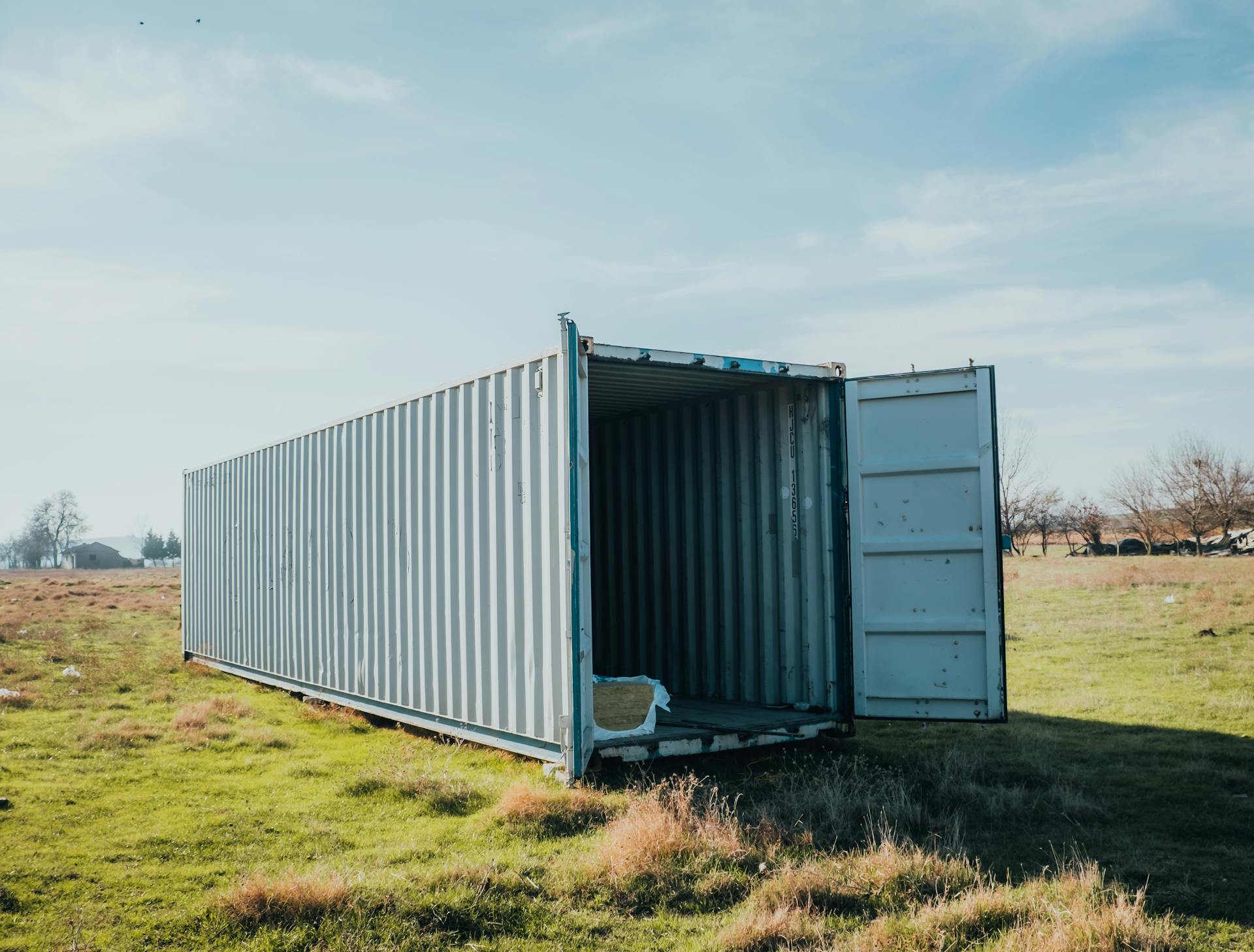 An open shipping container situated in a grassy field under a clear sky.