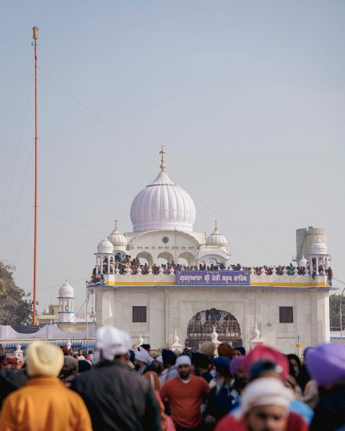 Free A vibrant gathering of people at a traditional Sikh Gurdwara, showcasing its striking architecture. Stock Photo