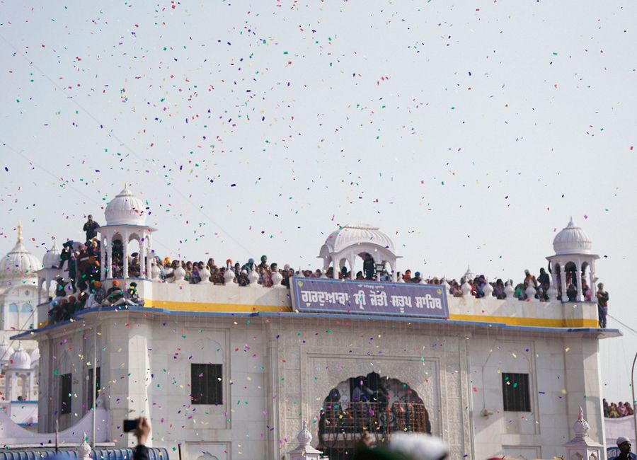 Crowds gather at a classic dome for a traditional festival with colorful confetti in the air.