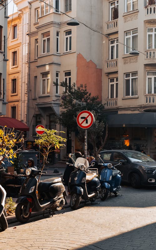 Free Motorcycles and Cars Parked in Front of a Residential Building in a City  Stock Photo