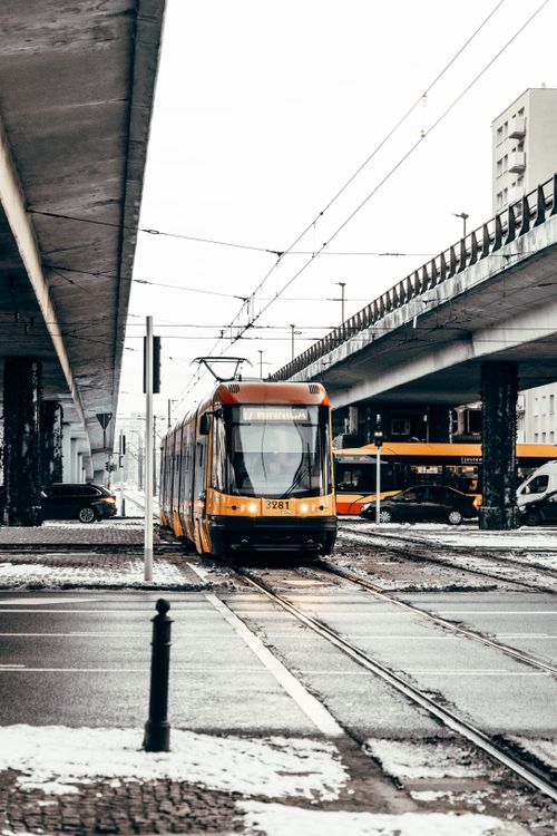 Free A yellow tram travels through a snowy urban landscape beneath overpasses. Stock Photo