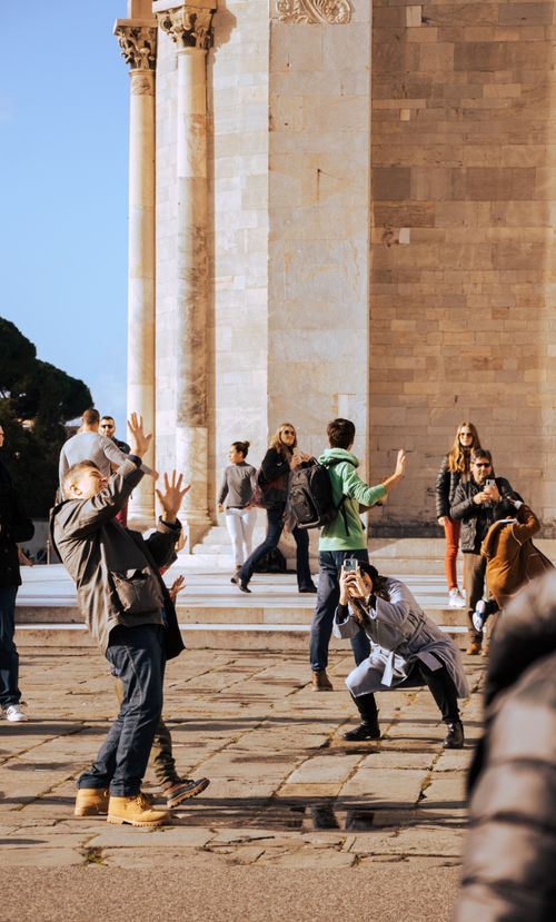 Free A lively scene of tourists posing and photographing near Pisa Cathedral on a sunny day. Stock Photo