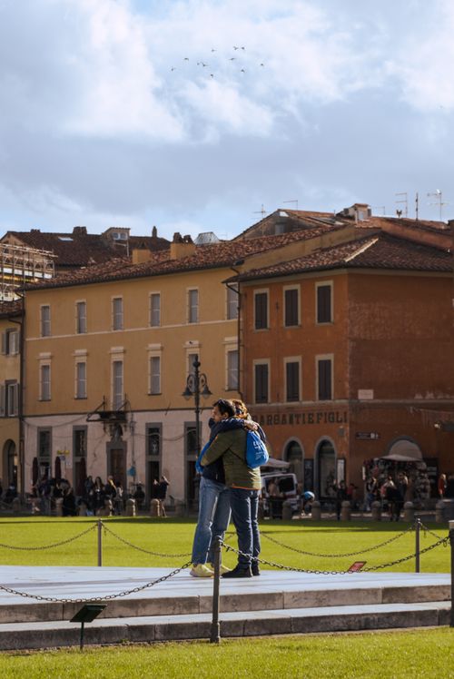 Free A couple hugging in a vibrant square in Pisa, Italy, depicting urban romance. Stock Photo