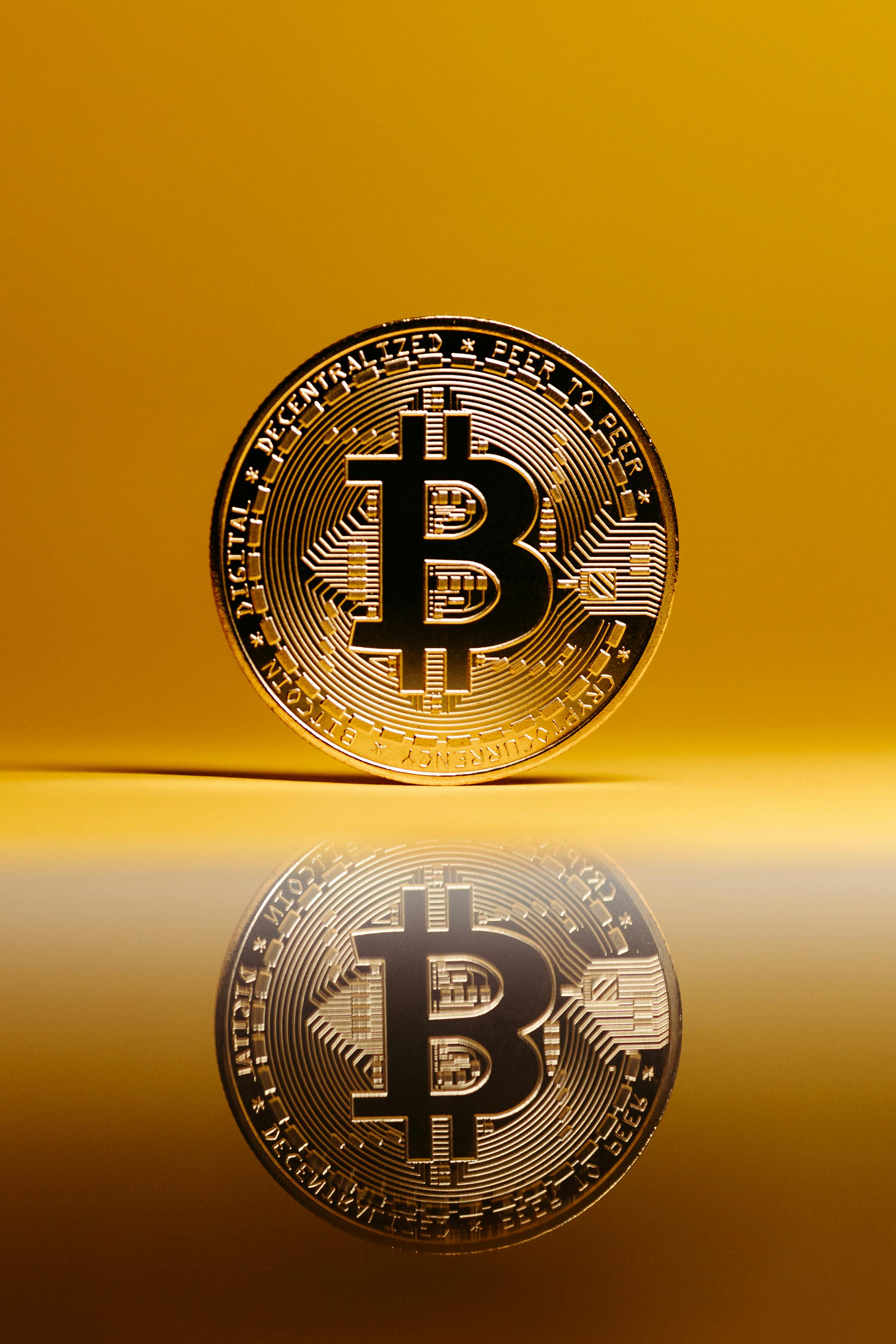 bitcoin with reflection on surface on yellow background