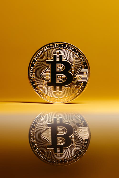 Bitcoin with Reflection on Surface on Yellow Background