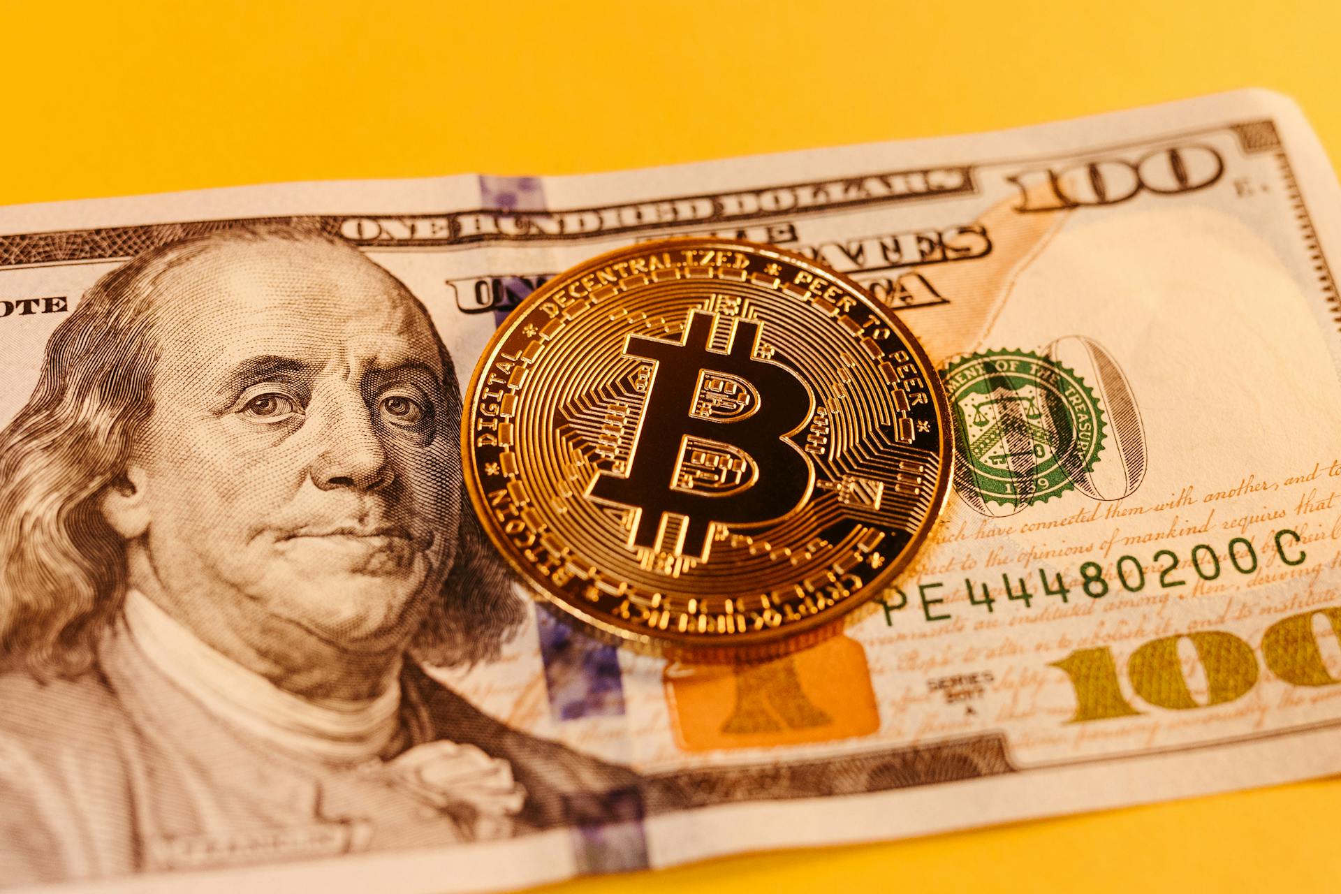 Close-up of a bitcoin on a US dollar bill, symbolizing digital currency and finance fusion.