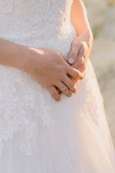 Close-up of a bride's hands in a lace wedding dress, showcasing elegance and romance.