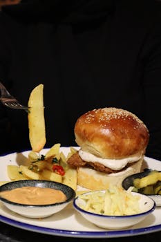Close-up of a juicy burger with fries and side dishes served in an Istanbul restaurant.