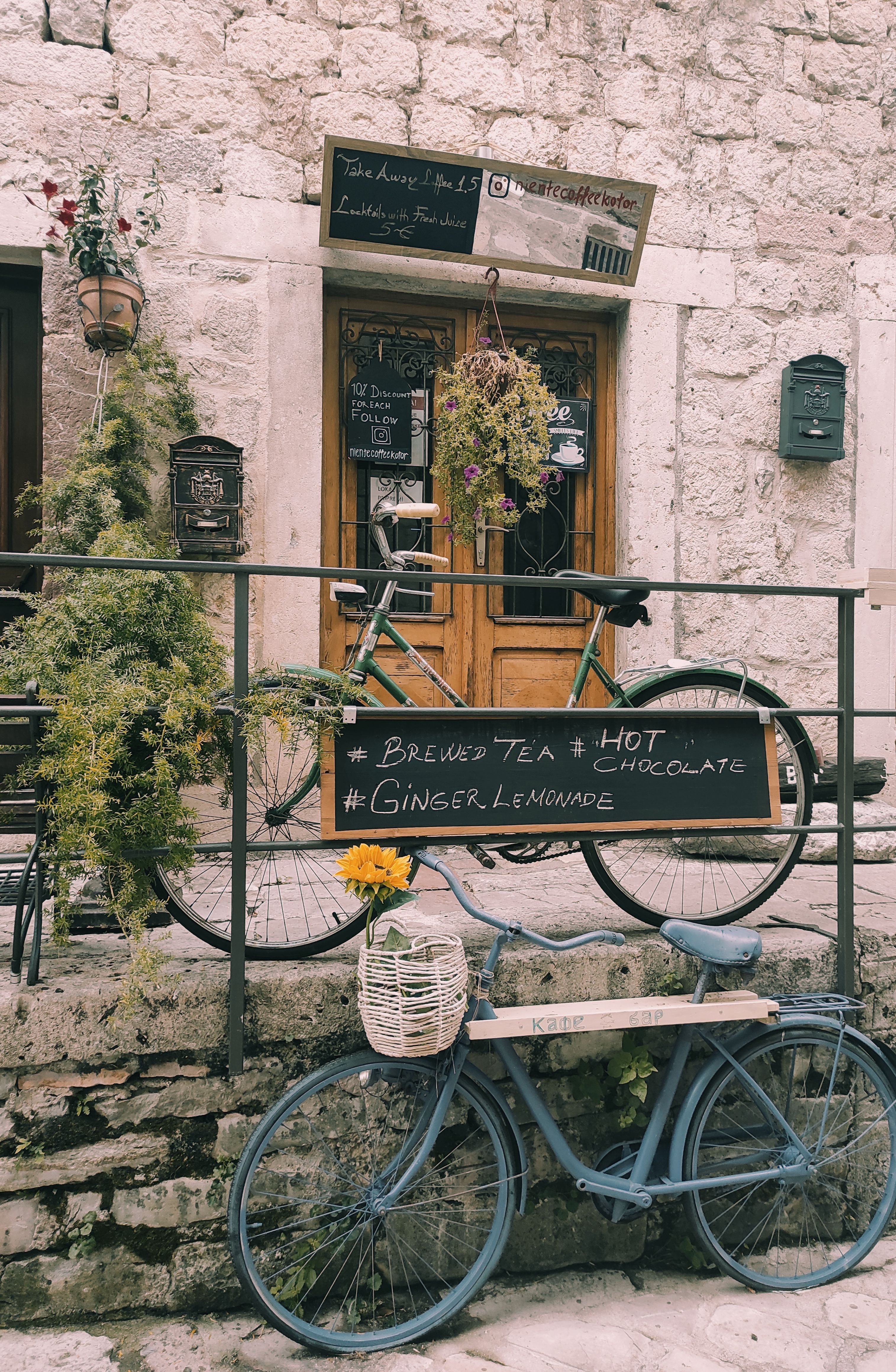 A quaint café in Kotor, Montenegro, featuring bicycles and a rustic stone wall. Perfect for capturing European charm.
