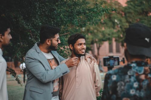 Free Two men casually interacting outdoors with a live recording setup, surrounded by greenery. Stock Photo