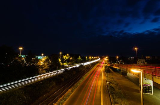 Vibrant long exposure shot capturing light streaks on a highway at night under dark blue skies.