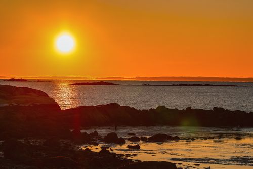 Free Beautiful sunset over the ocean with a vivid orange sky, capturing natural serenity. Stock Photo