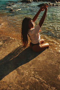 A woman in summer attire enjoys the beach at sunset with scenic ocean views.