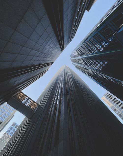 Free Dramatic low angle view of modern skyscrapers forming a cityscape against a blue sky. Stock Photo