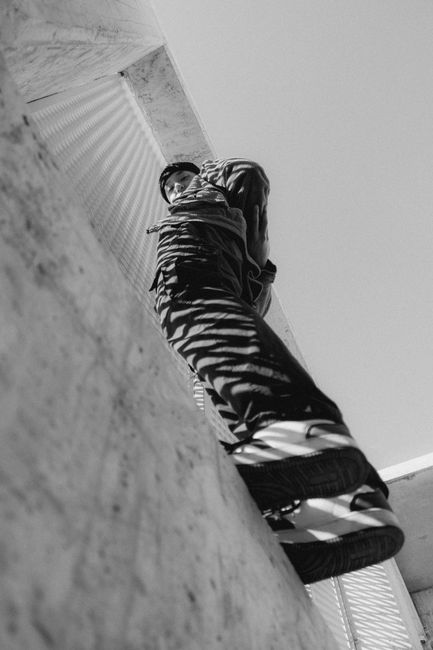 Low angle black and white photo of a man standing against a wall in Valletta, Malta.