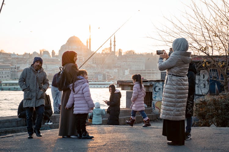 Woman Taking Picture Of Family Fishing From Bridge