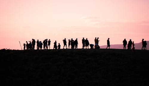 Group of People Walking on Road at Sunset