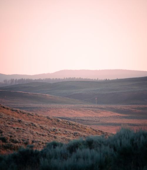 Free A tranquil sunrise highlighting rolling hills, offering a serene natural landscape. Stock Photo