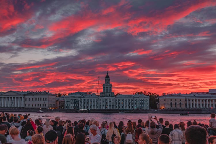 People Watching Red Sunset From Shore Of Neva In St Petersburg, Russia