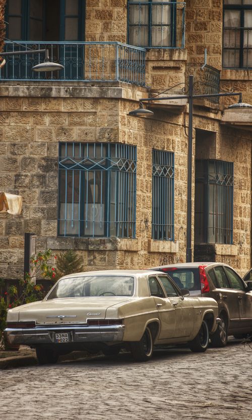 Free A classic vintage car parked on a cobblestone street beside historic brick buildings in Adana, Turkey. Stock Photo