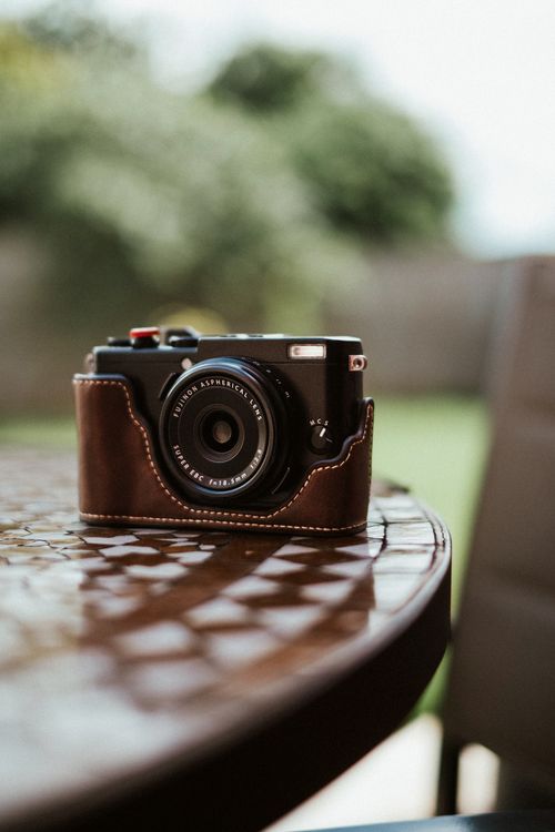 Free A modern camera in a leather case on an outdoor table. Stock Photo
