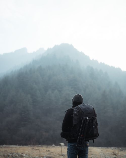 Free A lone backpacker traverses a foggy mountain landscape, embodying adventure and exploration. Stock Photo
