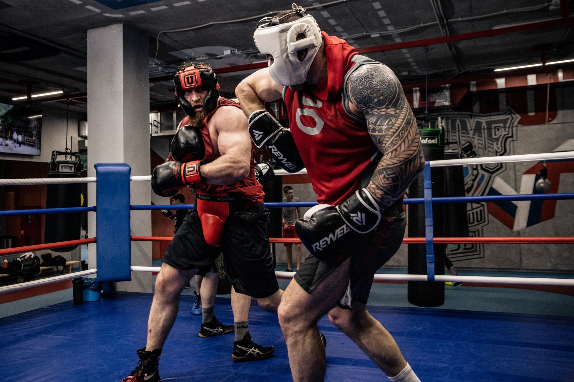 Two men engaged in an intense boxing sparring session in a gym ring.