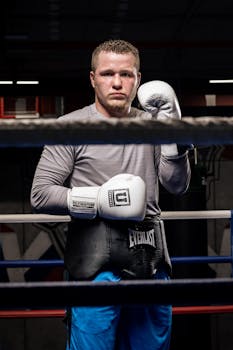 Portrait of a confident young male boxer standing in a gym ring ready to train.