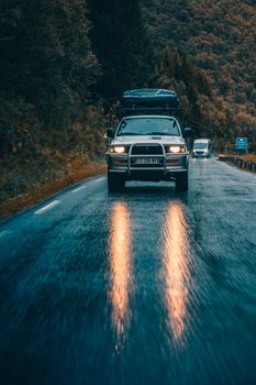Mitsubishi SUV driving on a rain-soaked road in Å, Norway. Front view with dramatic lighting.